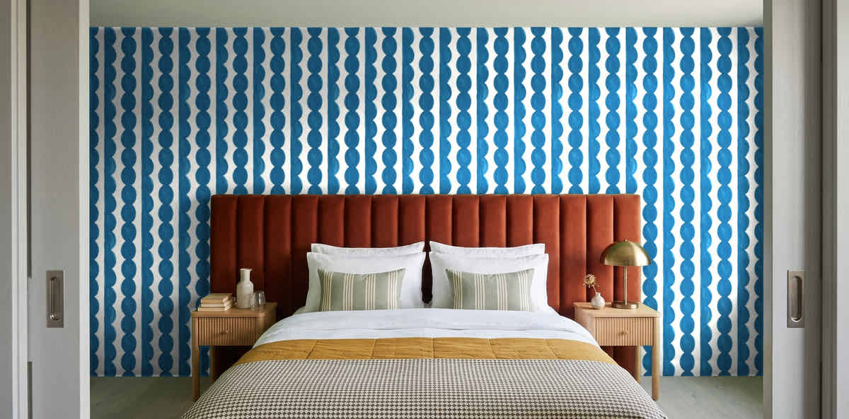 Papier peint Rayures festonnées – Bleu céruléen dans une chambre avec tête de lit terracotta